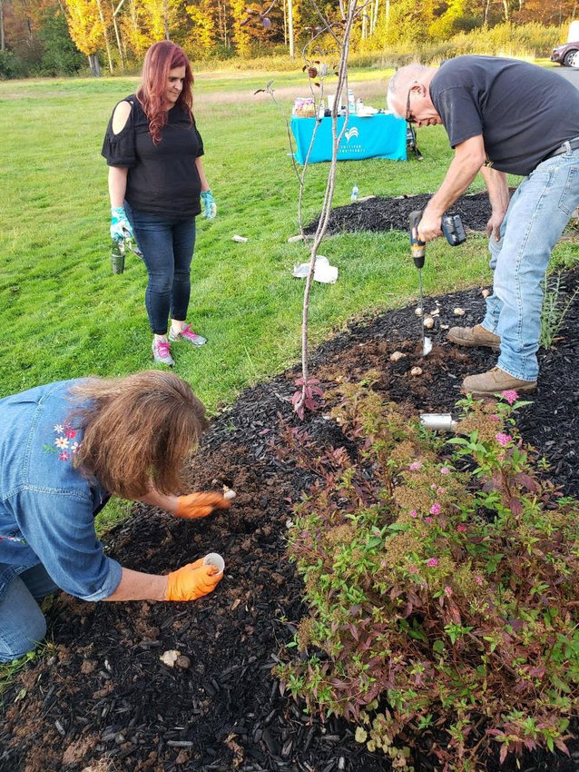 David Hosking helps with the bulb auger while Marion Hosking from White Sulphur Springs Sullivan First plants and fertilizes the bulb.